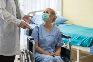 A doctor in a white lab coat holding a blister pack of medication while speaking to a female patient